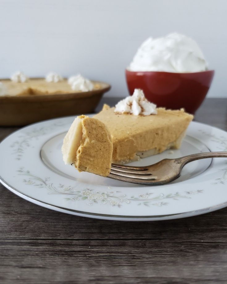 A bite of this easy keto pumpkin dessert with heavy cream in a bowl behind it