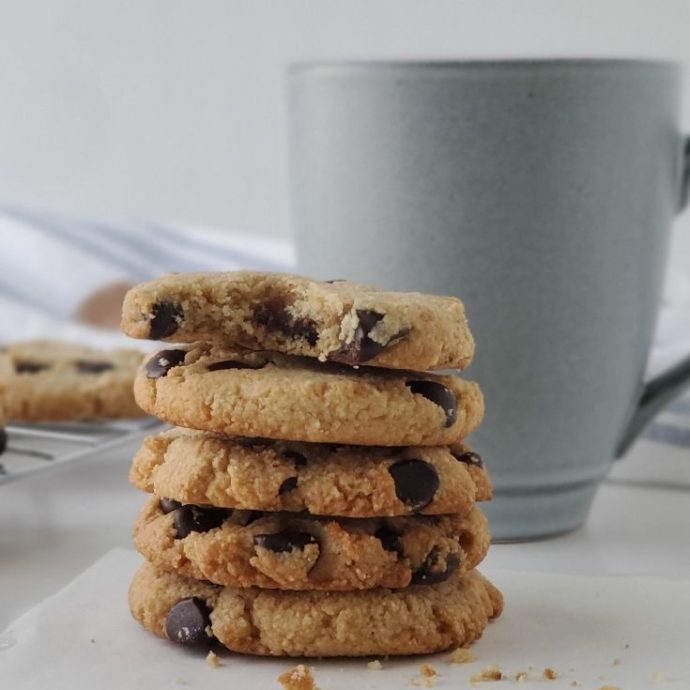 Keto Chocolate Chip Cookies stacked with a mug behind them
