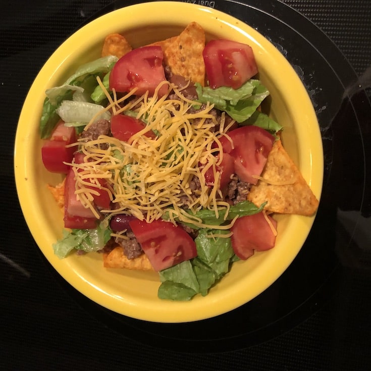 doritos, beef, beans, and vegetables with cheese in a bowl