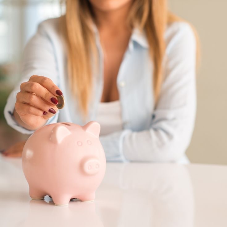 woman putting coin in a piggy bank