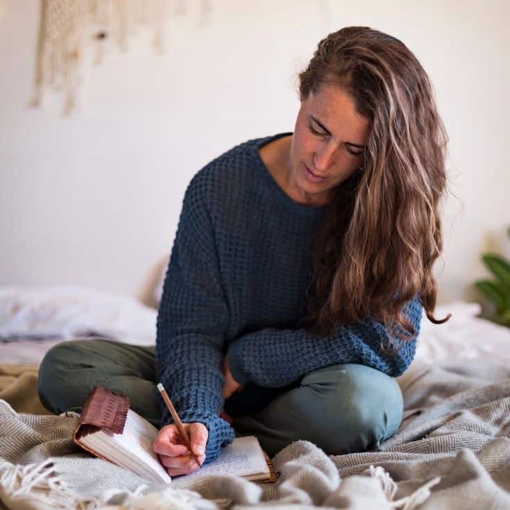 woman using the therapy journal prompts in her notebook