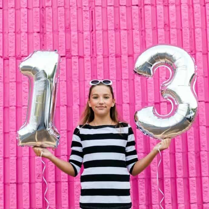 girl holding 13th birthday balloons
