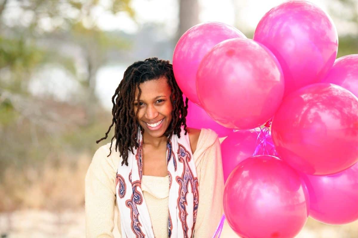 girl holding bright pink balloons smiling