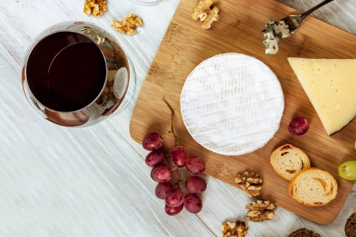 wine, cheese, nuts, and grapes on a board