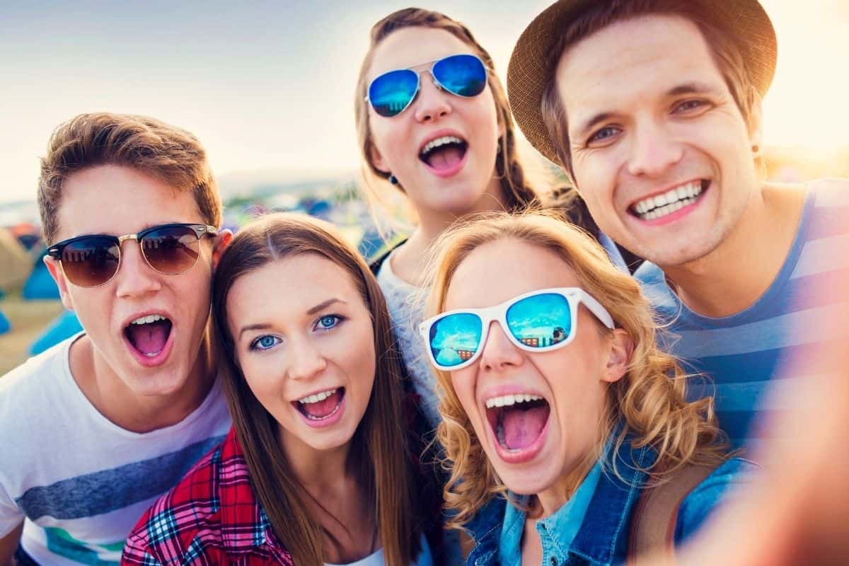 group of happy teens taking a selfie outside