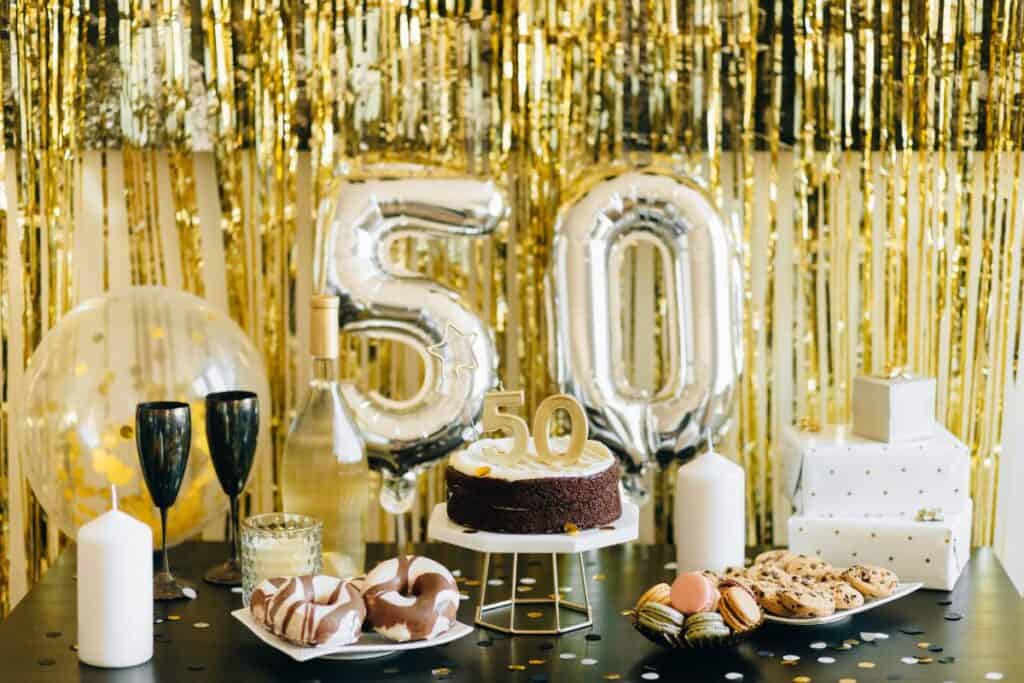 50th birthday party decor with balloons and a cake