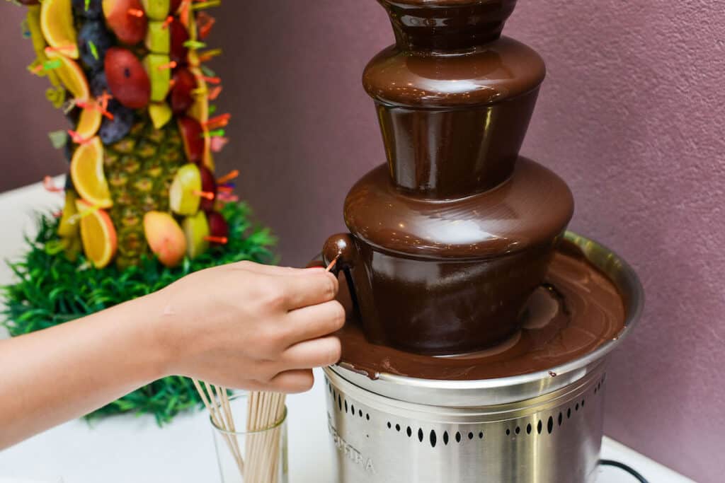 close up of someone dipping into a dark chocolate fountain