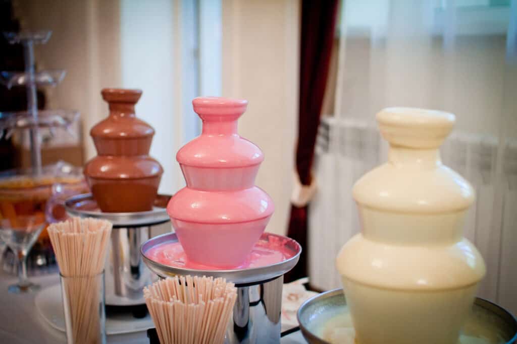 different colors of chocolate - 3 small chocolate fountains on a table