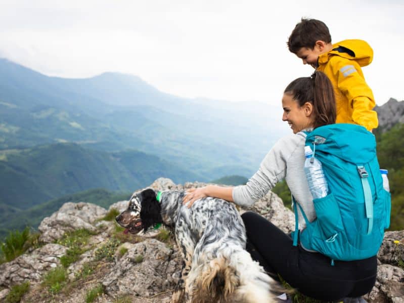 mom, son, and their dog on a hike in the mountains