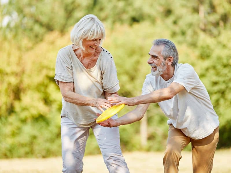 an older couple playing frisbee outside