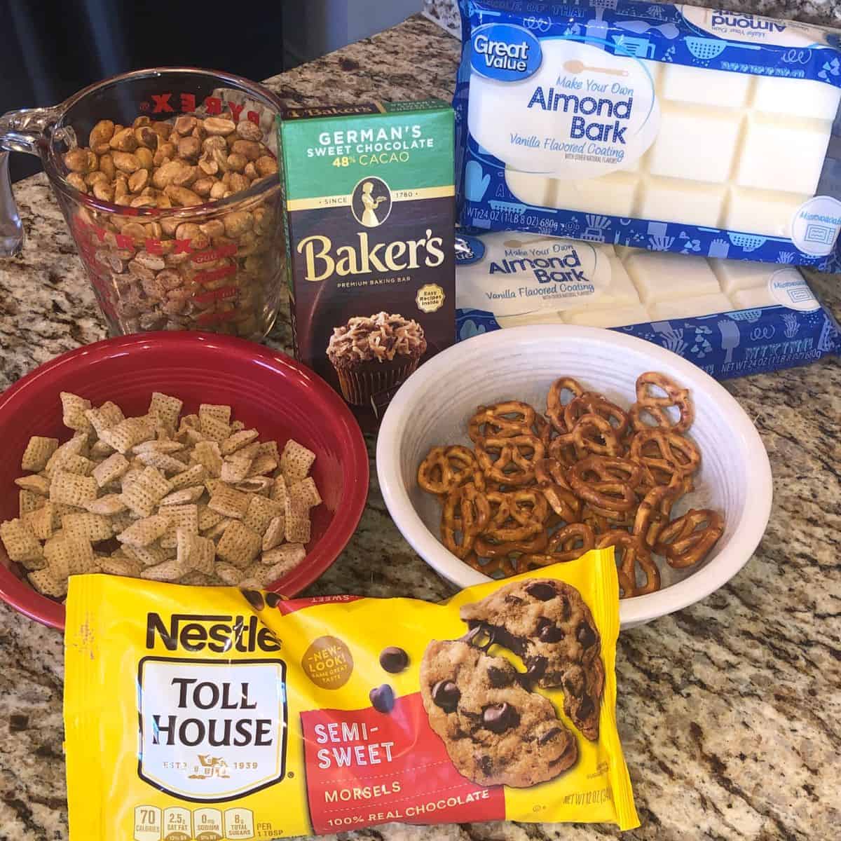 Christmas crockpot crack ingredients - peanuts, pretzels, chocolate chips, bakers chocolate, white chocolate bark, and chex mix
